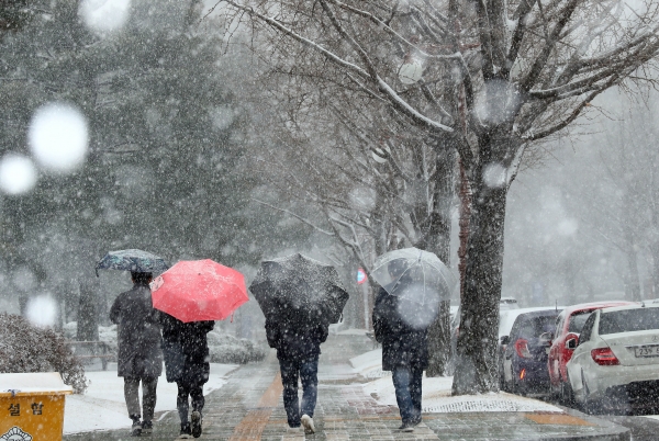 많은 눈이 내리는 지난 16일 서울 여의도 국회에서 시민들이 우산을 쓰고 지나가고 있다. (사진=뉴시스)