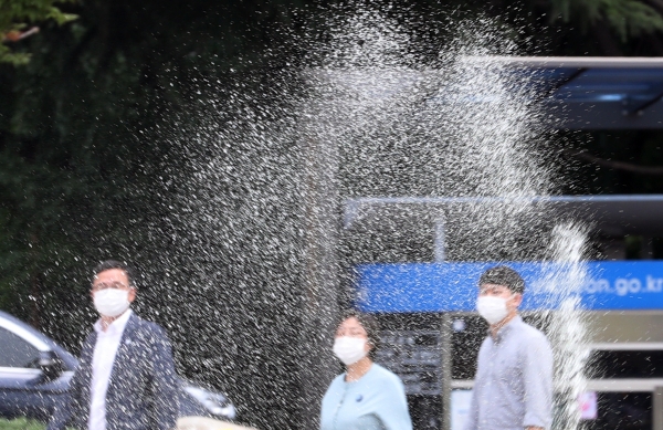 폭염이 이어지는 지난 23일 오후 시민들이 인천시 남동구 인천시청 앞 잔디에 물을 주는 스프링클러 옆을 지나치며 더위를 식히고 있다. (사진=뉴시스)
