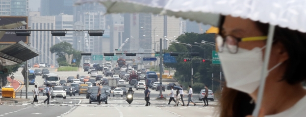전국 대부분의 지역에 폭염특보가 발효된 19일 오후 한 시민이 양산을 쓴채 서울 여의도공원 인근 횡단보도를 건너고 있다. (사진=뉴시스)