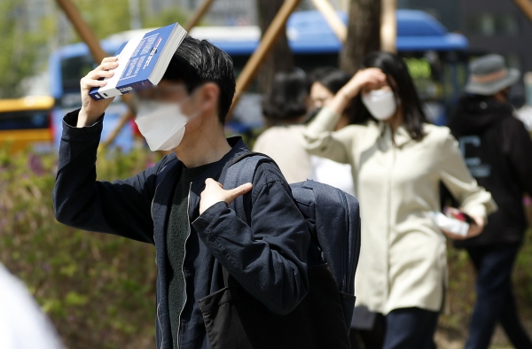 서울 낮 최고 기온이 28도로 무더운 날씨를 보인 21일 서울 중구 청계광장 인근에서 시민들이 책과 손으로 햇빛을 가리고 있다.(사진=뉴시스)