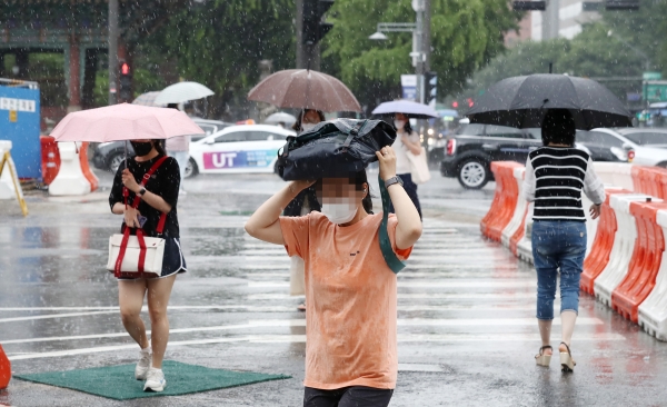 대기불안정에 의해 소나기가 내린 30일 오후 서울 종로구 광화문네거리 일대에서 한 시민이 가방을 머리에 쓰고 비를 피해 발걸음을 옮기고 있다.(사진=뉴시스)