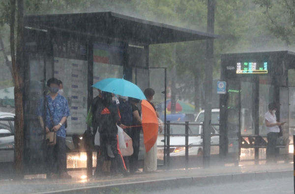 갑작스런 소나기가 내린 19일 오후 서울 종로구 숭인동 동묘앞역 버스정류장에서 시민들이 우산으로 쏟아지는 비를 막고 있다.(사진=뉴시스)
