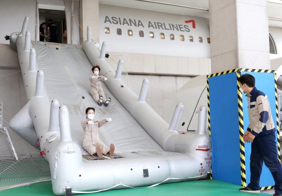 아시아나항공 캐빈 승무원들이 비상 탈출 훈련을 받으면서 슬라이드를 뛰어내리고 있다 (사진=아시아나항공 제공)