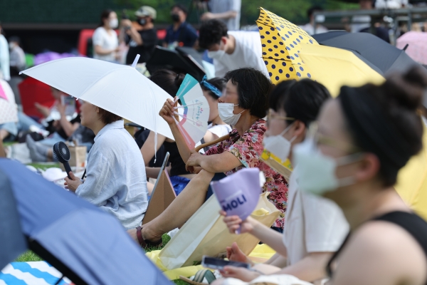 무더운 날씨를 보인 7일 오후 서울 시청광장에서 열린 '참신한 북 콘서트'에서 관람객들이 우산을 쓴 채 부채질을 하고 있다 (사진=연합뉴스)