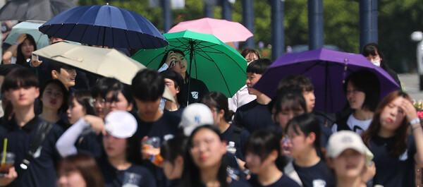 무더운 날씨를 보인 15일 오후 대구 강창교 인근 금호강 둔치에서 열린 계명대학교 'WALK 124' 걷기 행사에 참여한 학생들이 햇볕을 가리며 걷고 있다.(사진=연합뉴스)