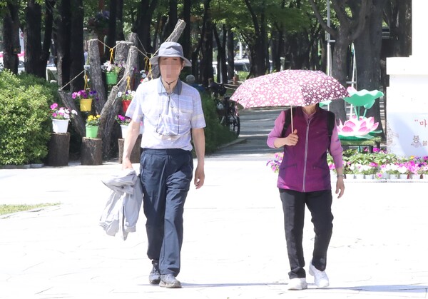 16일 오후 2시 기온이 30도가 넘어간 대전 서구 둔산동 보라매공원에서 양산을 쓴 시민과 모자를 쓴 시민이 햇볕을 피해 산책하고 있다(사진=연합뉴스)
