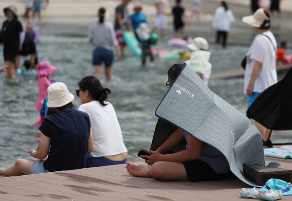 무더운 날씨가 이어진 2일 오후 여의도 한강공원 물놀이장을 찾은 한 시민이 돗자리로 그늘을 만들어 더위를 식히고 있다 (사진=연합뉴스)